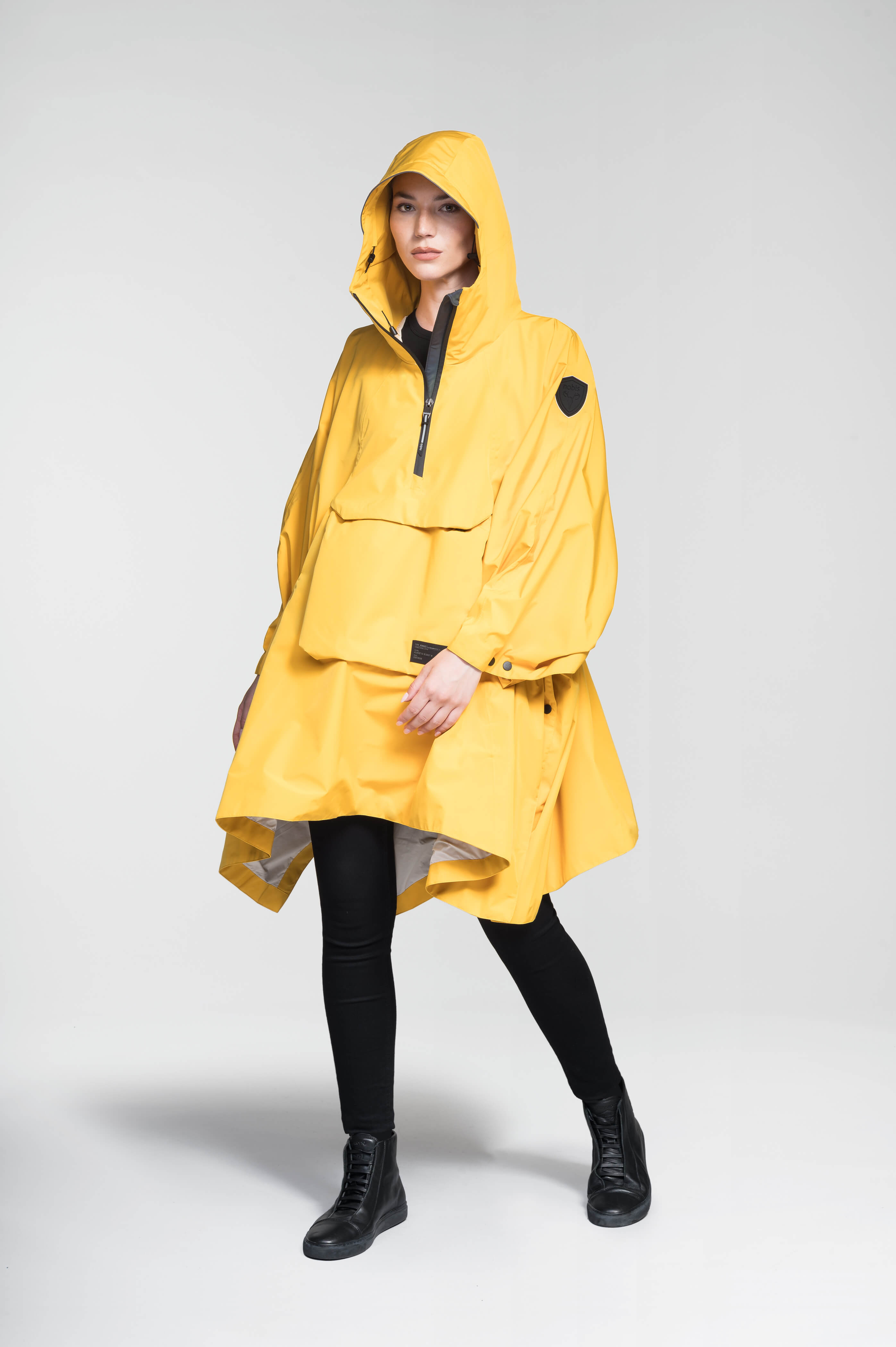 Hydra Unisex Performance Poncho in thigh length, non-removable hood, vertical half-zipper along centre front collar, hidden side-entry waist zipper pockets, adjustable webbing straps and snap closure cuffs, and packable to front kangaroo pocket with flap opening, in Old Gold